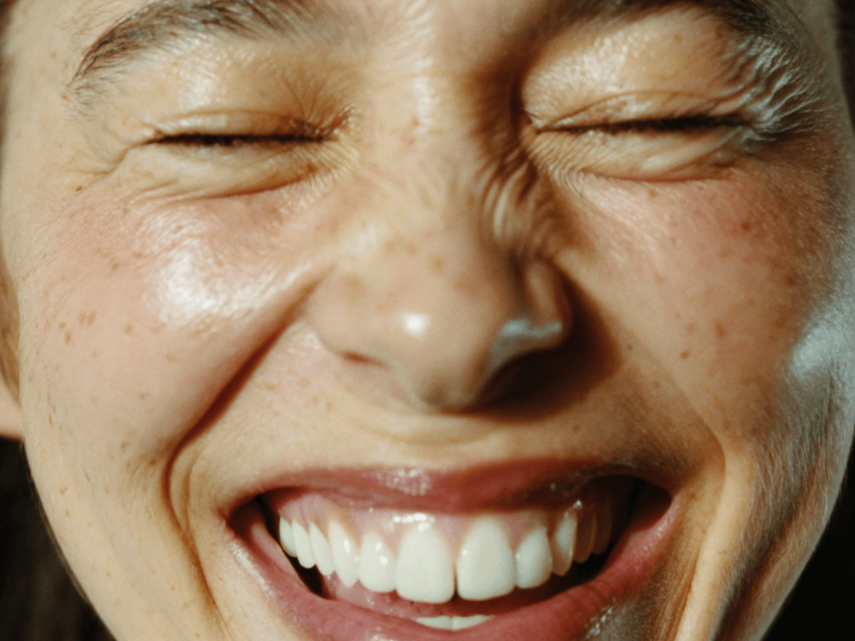 Close-up of a person laughing with their eyes closed
