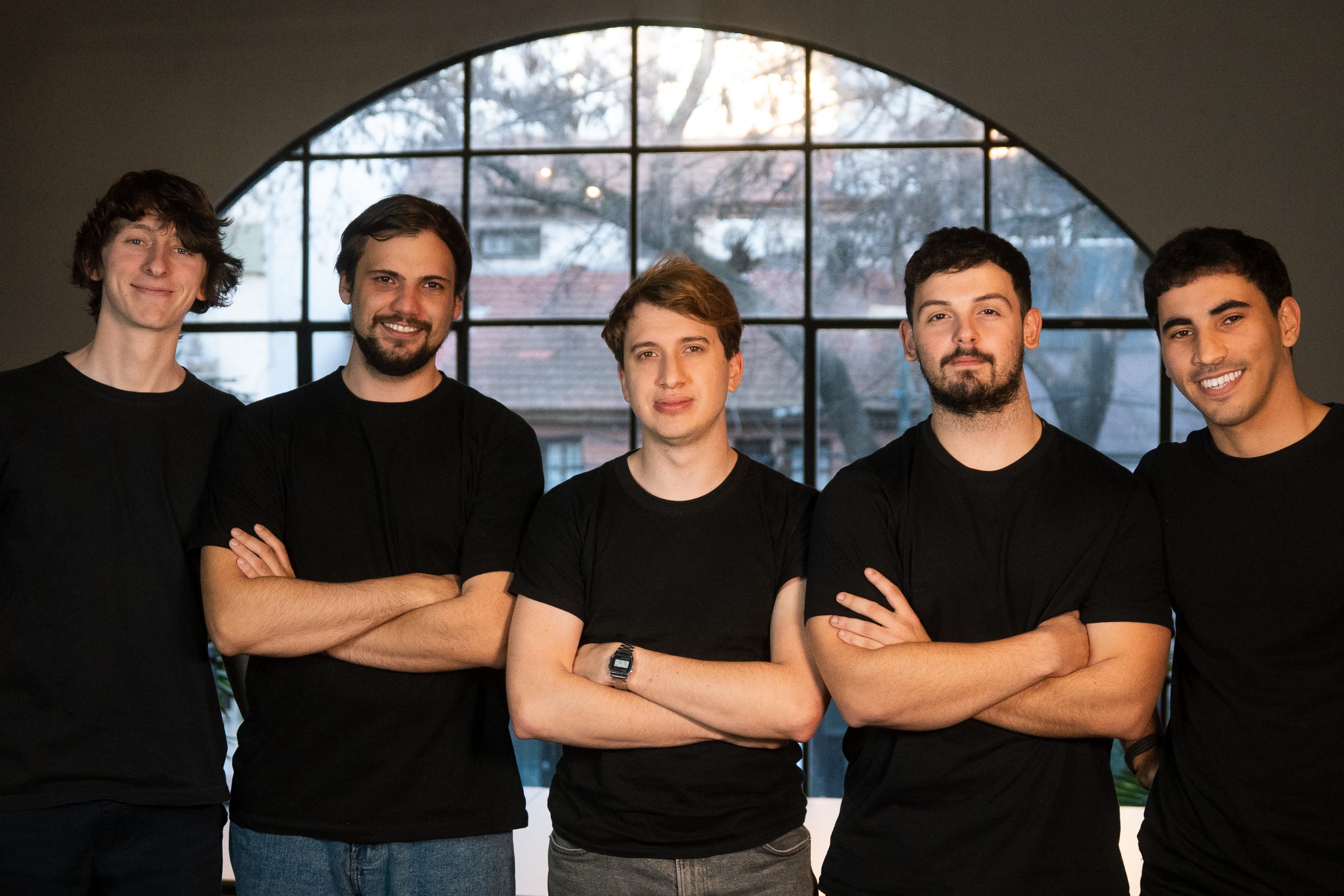 The five founders of Loybox, standing in front of an arched window at the Buenos Aires office