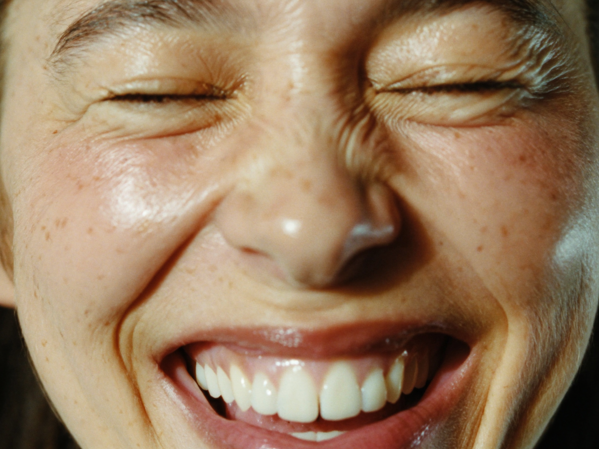 Close-up of a person laughing with their eyes closed