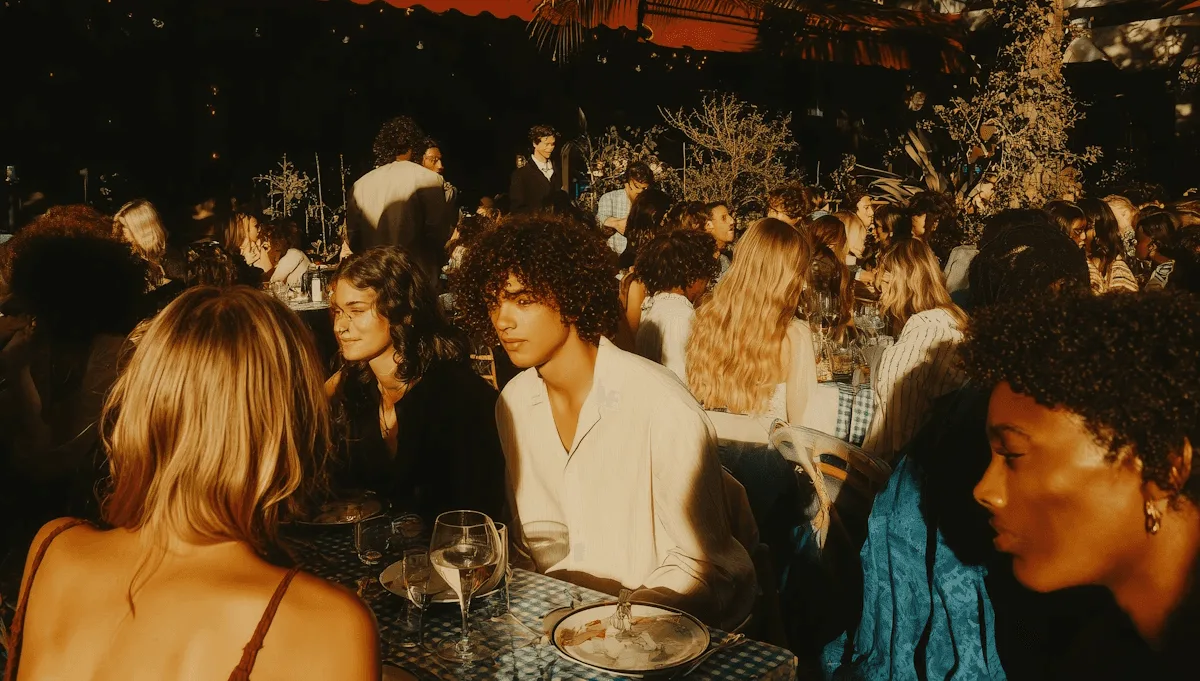Una mesa larga llena de gente cenando en una terraza de noche