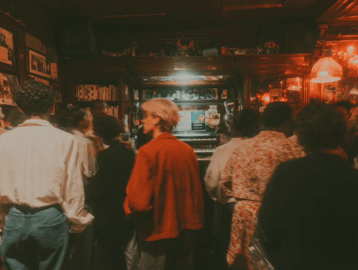 Gente en la barra de un bar lleno, iluminada con luz roja