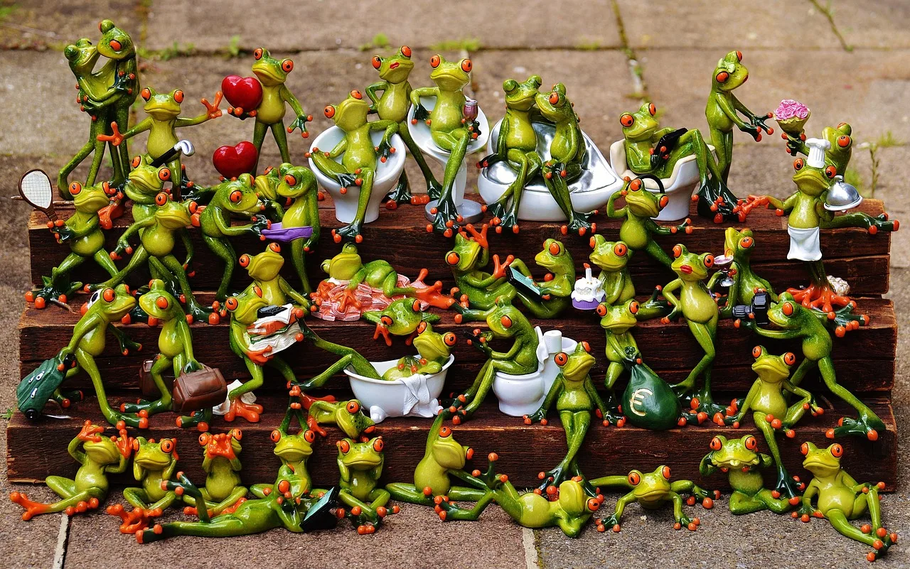 Decenas de figuras de ranas de colores acomodadas en escalones de madera, cada una con su propio objeto