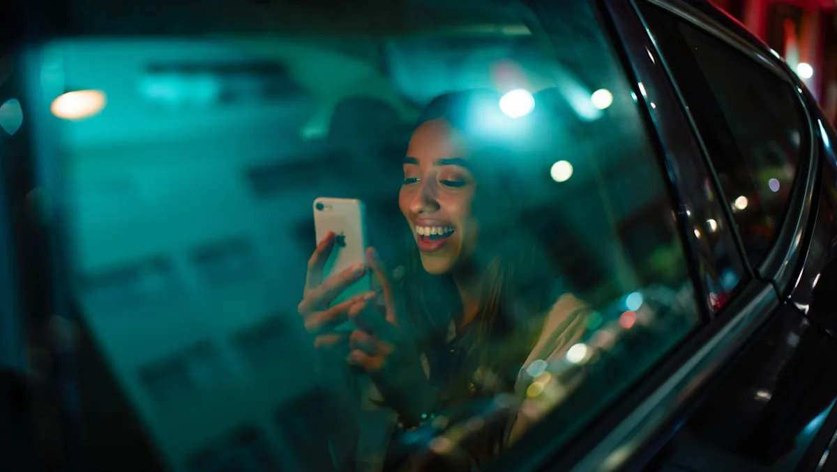 Una mujer dentro de un auto mira su teléfono y sonríe