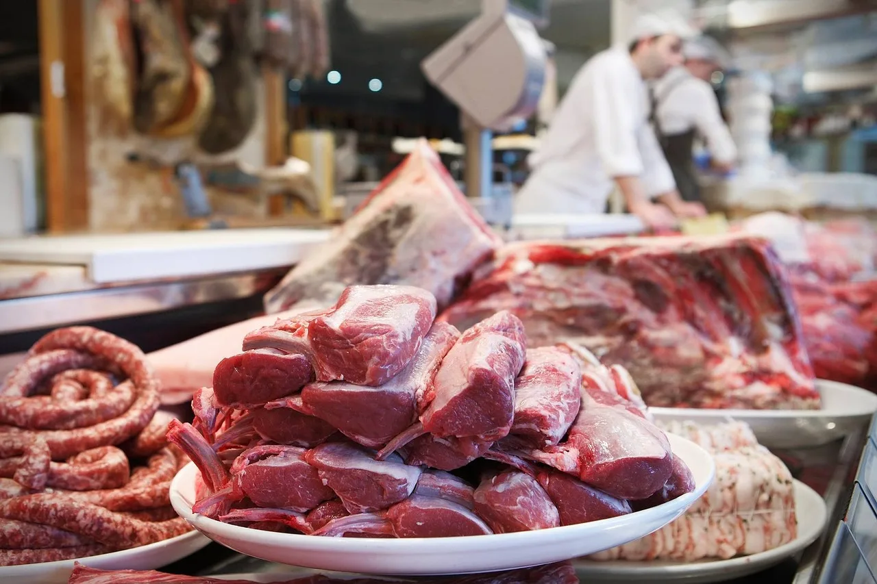 Una bandeja con cortes de carne roja y chorizos en el mostrador de una carnicería con dos carniceros trabajando al fondo