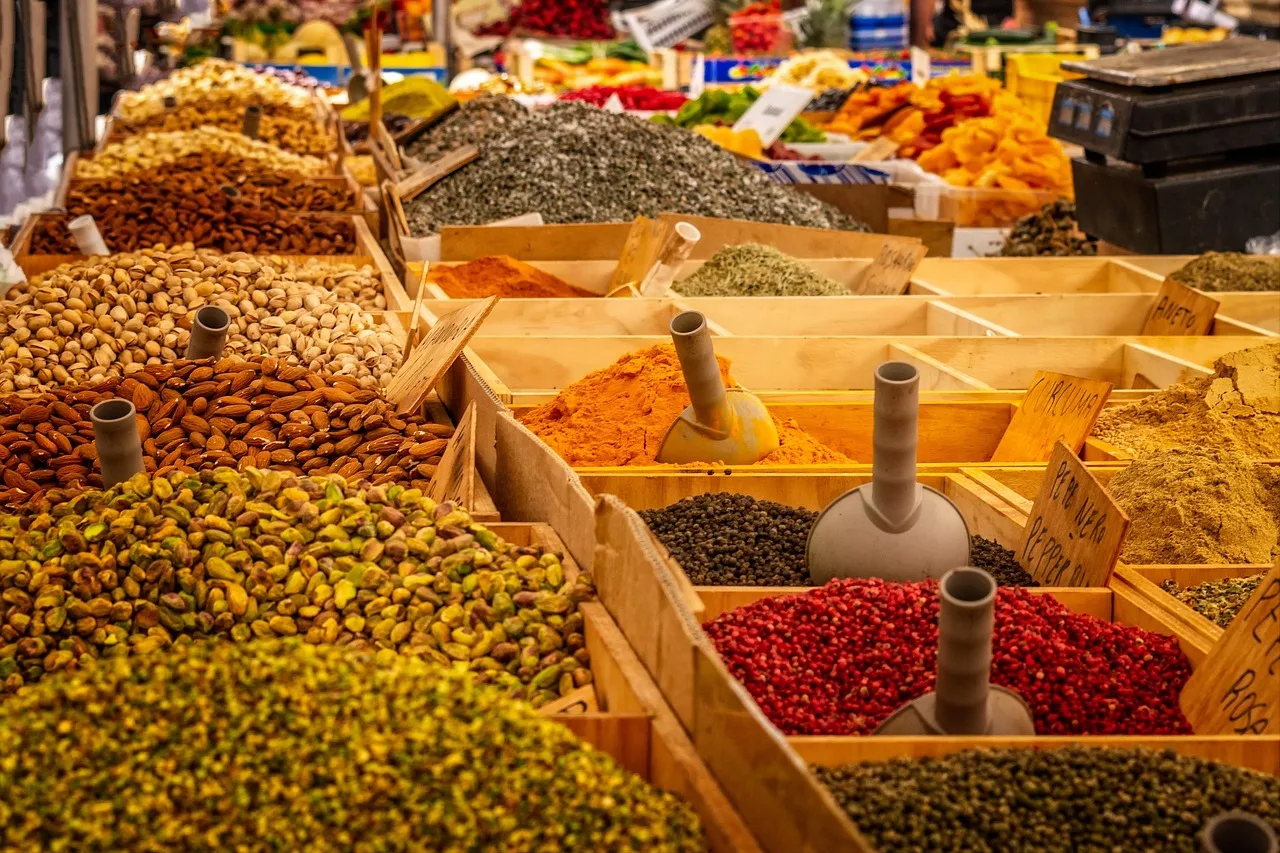 Cajones de madera con almendras, pistachos, semillas y especias a granel con sus cucharas en un puesto de mercado