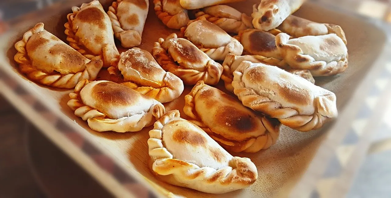 Una charola de empanadas recién horneadas, con el borde dorado, acomodadas una al lado de la otra